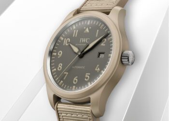 A beige IWC Schaffhausen Pilot's Watch automatic wristwatch with a fabric strap, gray dial, white numerals, and date display, inspired by the Mojave Desert, photographed on a white background.