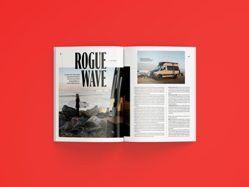 Open magazine on a red surface, displaying a feature article titled "Rogue Wave" from the July 2025 duPont REGISTRY, with a photo of a person by rocks and another of a van parked near water.