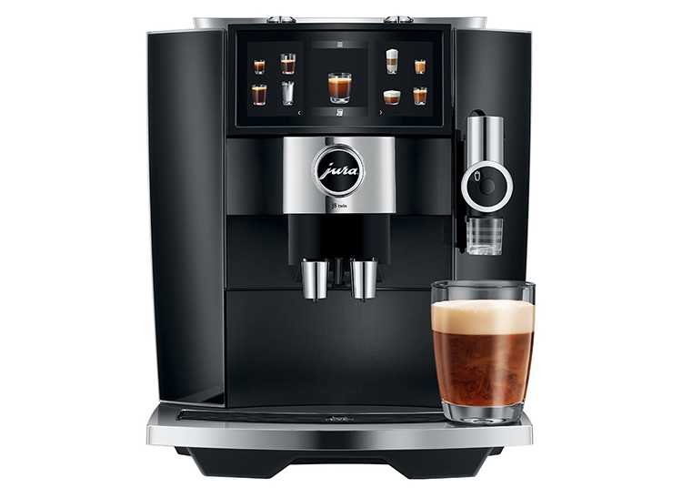A black Jura automatic coffee machine with a digital display and a clear glass of cappuccino on the drip tray—perfect for refined living and elevating your kitchen with luxury home accessories.