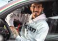 A man wearing a white Ducati hoodie sits in the driver's seat of a car, smiling at the camera with his hand resting on a helmet—wondering what two-time MotoGP champ Francesco Bagnaia makes of the Lamborghini Temerario.