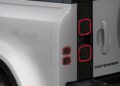 Close-up of the rear left taillight and "Defender" badge on a silver Land Rover Defender Refreshed: Here's What’s New For 2026 SUV, with part of the spare tire visible.