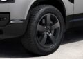 Close-up of a matte black alloy wheel and tire on a silver Land Rover Defender Refreshed: Here's What’s New For 2026 SUV, photographed from the side, showing part of the front bumper and fender.