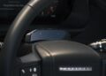 Close-up of a Land Rover Defender Refreshed: Here's What’s New For 2026, highlighting its steering wheel, dashboard, control stalks, buttons, and advanced digital display screen behind the wheel.