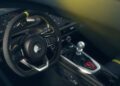 Steering wheel and manual gear shift of a Lotus Emira V6 sports car, with yellow stitching and accents visible on the interior.