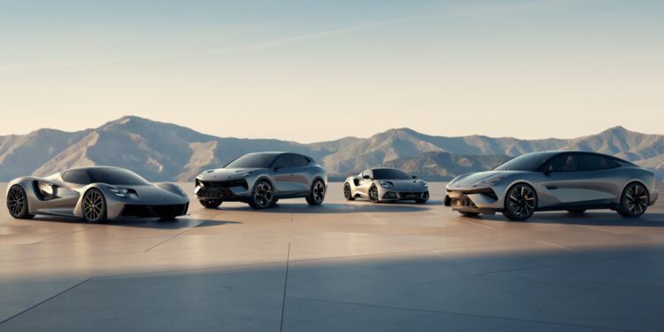 Four modern silver sports cars are parked side by side on a flat surface with mountains and a clear sky in the background.