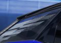 Close-up of a 2026 Optiq-V Cadillac’s rear window featuring white and blue geometric line patterns, with a blurred blue background—reflecting the bold presence of its 519HP power.
