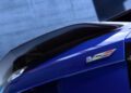 Close-up of a blue 2026 Optiq-V’s rear with a carbon fiber spoiler, Cadillac badging, and a bold V-Series emblem on the trunk—hinting at its impressive 519HP performance.