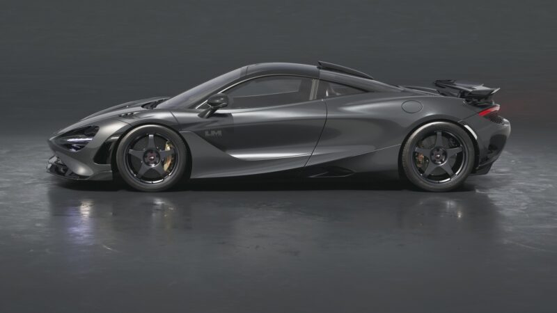 Side view of the Limited-Run 750S Le Mans Edition, a sleek, dark gray sports car with aerodynamic design, low profile, and large alloy wheels, displayed on a reflective surface—celebrating McLaren's iconic 1995 debut race win.