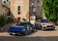 Two Maserati vehicles, one blue and one bronze, are parked on a cobblestone street in front of an old brick and stone building with archways, capturing the spirit of historic cars at the 1000 Miglia.