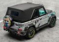 A customized Mercedes-Benz G-Class with cartoon and graffiti-style artwork, neon green accents on wheels, and a black soft top, parked indoors on a gray tiled floor.