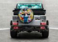 Rear view of a Mansory G-Wagon with a colorful Alec Monopoly-themed spare tire cover and turquoise interior visible.