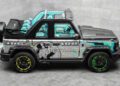 A custom Mansory G-Wagon with a turquoise interior, graffiti-style paint, green-accented wheels, and an Alec Monopoly character graphic sits parked in a gray tiled room.