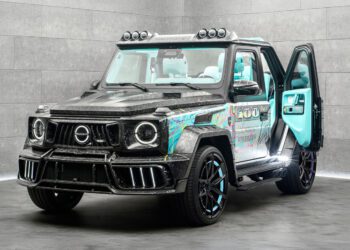 A customized Mansory G-Wagon with a carbon fiber body, colorful graphic accents, black wheels, and a turquoise interior, parked indoors with the driver's door open.