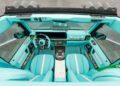 Interior view of a Mansory G-Wagon with turquoise seats, steering wheel, and dashboard, featuring diamond stitching and colorful accents, viewed from above.