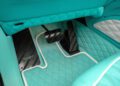 Turquoise quilted car floor mat with white trim, black carbon fiber pedals, and a Mansory logo on the driver’s side footwell, perfectly tailored for the luxurious G-Wagon.