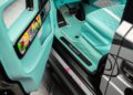 The image shows the interior of a luxury G-Wagon with turquoise quilted seats, custom floor mats labeled "MANSORY," and colorful cartoon-style door trim accents inspired by Alec Monopoly.