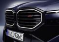 Close-up of the front grille of a dark blue BMW XM Label vehicle with the "XM" badge and a European license plate reading "M EI 936E.