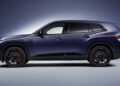 Side view of a dark blue 2026 BMW XM luxury SUV with black wheels and red brake calipers, shown against a gradient background.