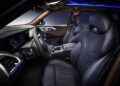 Modern car interior of the 2026 BMW XM featuring black leather seats, digital dashboard displays, a navigation screen, ambient blue lighting, and a multi-function steering wheel.
