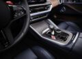 Close-up of the luxurious 2026 XM interior showing a modern gear shifter, control buttons, blue leather seats, and part of the steering wheel.