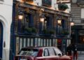 A maroon Rolls-Royce SUV is parked on the street in front of the historic Lapérouse restaurant in Paris, making a bold statement during Paris Fashion Week.