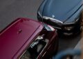 A grey Rolls-Royce Spectre sedan and a red SUV are parked closely on a city street, viewed from above, capturing a moment of elegance reminiscent of Paris Fashion Week.