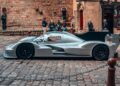 A sleek silver 1-of-1 Porsche 963 RSP breaks cover as a tribute to Penske ahead of Le Mans 2025, parked on a cobblestone street with onlookers admiring it near old stone buildings.