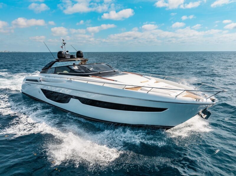 A modern white motor yacht cruises across open water under a partly cloudy sky, creating waves as it moves forward—a true maritime experience for those seeking luxury yachts.