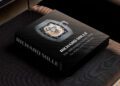 A hardcover coffee table book titled "Richard Mille: The Impossible Collection" by Assouline rests on a dark cushioned surface, featuring a detailed watch on the cover.