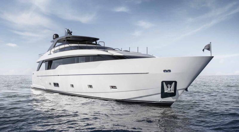 A modern white yacht floats on calm ocean water under a partly cloudy sky, viewed from the front side angle, showcasing the ultimate maritime experience in luxury yachts.