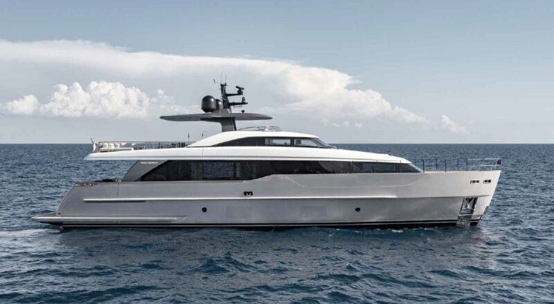 A modern white luxury yacht is anchored on calm blue ocean water under a partly cloudy sky, offering the ultimate maritime experience.