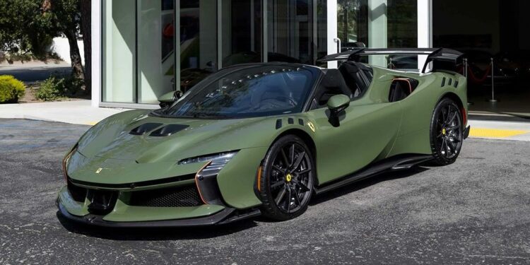 A matte Verde Oliva SF90XX Spider Ferrari convertible is parked outside a modern glass-walled building on a paved surface, capturing the essence of Ferrari Westlake style.