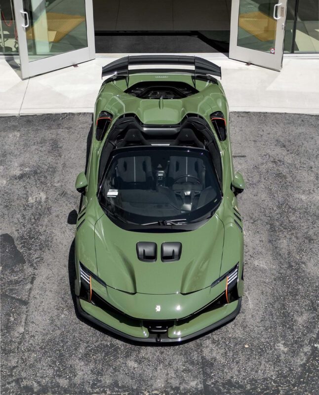 Overhead view of a Verde Oliva Ferrari SF90XX Spider parked on a paved surface in front of an open building entrance, showcasing the striking style at Ferrari Westlake.