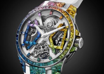 The Limited-Edition Ulysse Nardin Blast 'Sparkling Rainbow' features an exposed mechanical movement and a bezel adorned with multicolored gemstones, set on a chic white strap for true luxury flair.