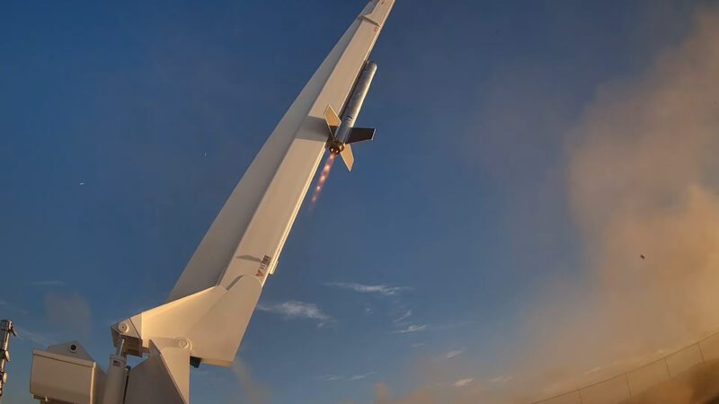 A rocket is launching vertically into the sky, emitting flames and smoke against a clear blue sky—reminding us of future possibilities like flying from Miami to Dubai in 2 hours aboard a 4600 mph hypersonic jet.