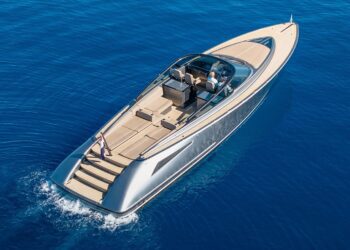 A modern luxury motor yacht with a sleek design travels on calm blue water, offering an unforgettable maritime experience for two people relaxing in the cockpit.