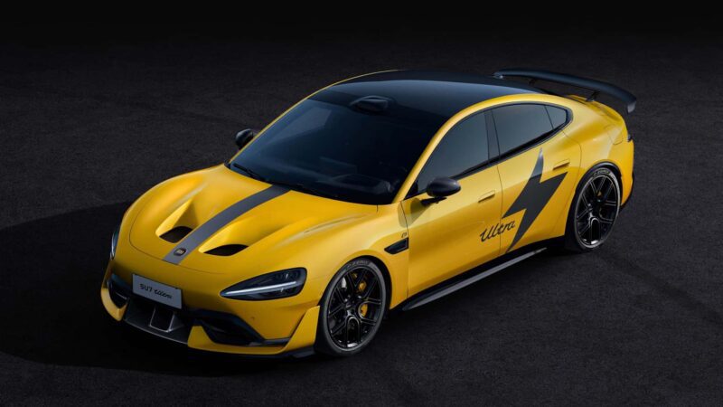 A yellow sports car with black racing stripes, a large rear spoiler, and a lightning bolt graphic on the side is parked on a dark surface, inspired by Nürburgring legends.
