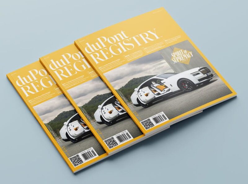 Three copies of duPont REGISTRY magazine, perfect for any Father's Day Gift Guide, feature a yellow cover with a white sports car and the headline "Sports Supremacy," stacked on a light blue surface.