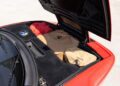 The open front trunk of this rare Ferrari 512 TR Prototype reveals black carpeting, a fuel cap, and tan bags with a horse logo, alongside a red fabric item.