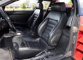 Interior of a rare Ferrari 512 TR Prototype with two black leather seats, a center console featuring unique controls, and a glimpse of the dashboard and door—showcasing pre-production Ferrari details.