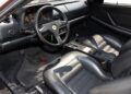 Interior of a rare Ferrari 512 TR Prototype featuring black leather seats, a three-spoke steering wheel, and analog gauges on the dashboard.