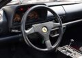 Black steering wheel with Ferrari logo, analog gauges on the dashboard, and a manual gear shifter in the center console of this rare Ferrari 512 TR Prototype pre-production interior.
