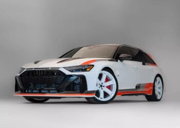 A white Audi RS6 Avant, an exotic car with red and black accents, white wheels, and tinted windows is photographed in a studio with a neutral background.