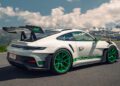A white Porsche 911 GT3 RS with green wheels and accents is parked on a mountain road under a partly cloudy sky, reminiscent of the legendary FAT Mankei route.