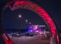 A modern metal arch illuminated in red frames a parking lot with sports cars at night, leading to a building with a sign that reads "Porsche Experience Center Toronto," highlighting the allure of the Toronto Experience Center.