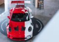 A red and white Porsche sports car with a maple leaf design is displayed indoors on a circular platform at the Toronto Experience Center.
