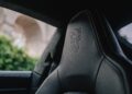 Close-up of a car's black leather seat with an embossed lion crest, visible stitching, and a blurred outdoor background through the window—echoing Porsche Sonderwunsch luxury with Luxembourg-inspired detailing.