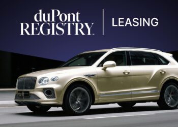 A gold luxury SUV drives in front of a dark blue background with "duPont Registry Leasing" text displayed above, highlighting exceptional car leasing options for exotic vehicles.
