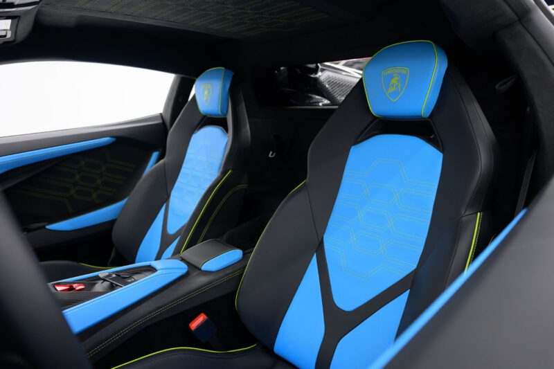 Interior of a Limited Spec 2025 Lamborghini featuring two black and blue leather seats with neon green accents and Lamborghini logos on the headrests.