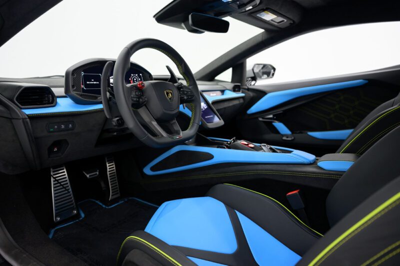 Interior view of a 2025 Mansory Lamborghini Revuelto in the U.S., featuring blue and black leather seats, a digital dashboard, and modern controls.